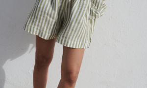 Woman wearing a cropped white linen top with a loose-fitting olive stripes linen shirt and matching shorts with pockets