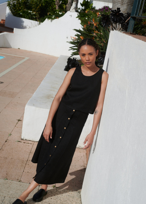 Model wearing a black midi skirt paired with a matching casual sleeveless linen top