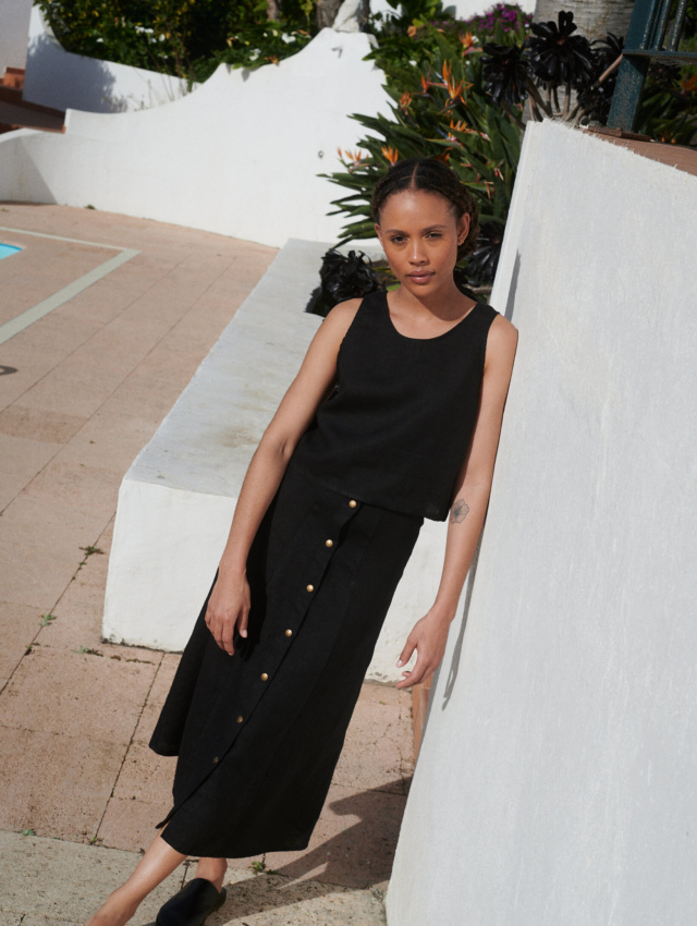 Model wearing a black midi skirt paired with a matching casual sleeveless linen top