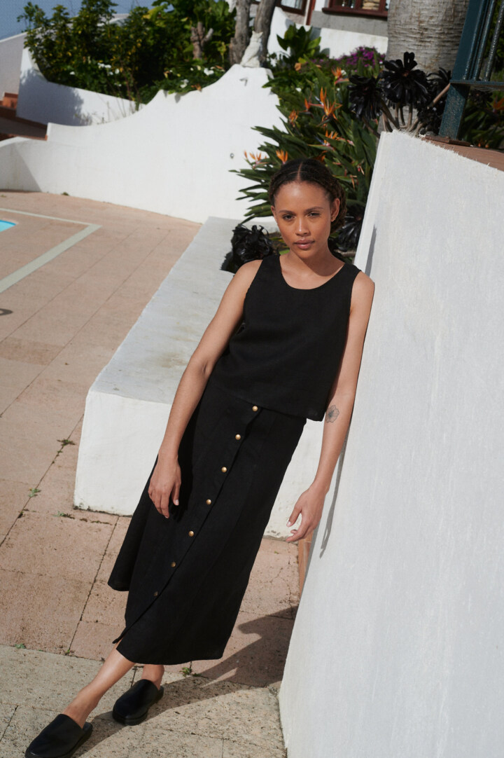 Model wearing a black midi skirt paired with a matching casual sleeveless black linen top