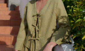 a woman wearing a linen set featuring a tie-up front top paired with a short skirt in olive linen fabric