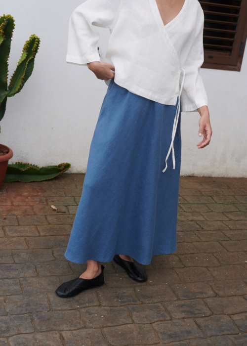 A flared blue linen maxi skirt and an oversized milky white linen top with long sleeves and a deep V-neck outfit