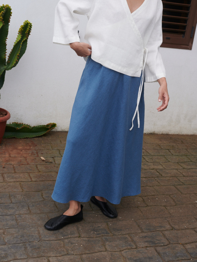 A flared blue linen maxi skirt and an oversized milky white linen top with long sleeves and a deep V-neck outfit