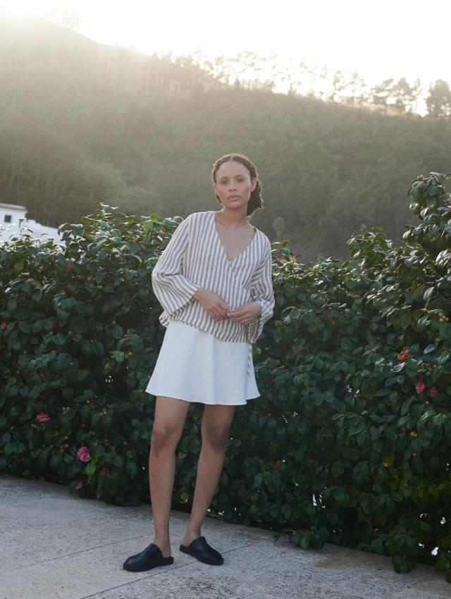 a woman wearing a wrap top in light linen stripes paired with a milky white linen short skirt