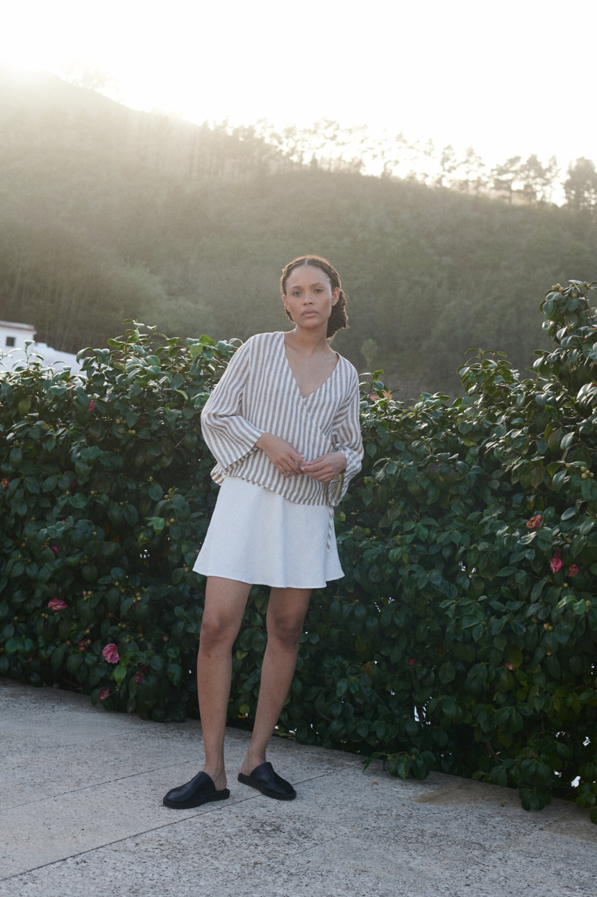 a woman wearing a wrap top in light linen stripes paired with a milky white linen short skirt