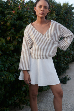 A light linen cacao stripes wrap top paired with a milky white linen short skirt adds a touch of summer style to the woman's look