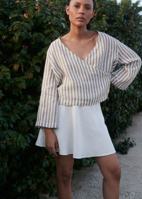 A light linen cacao stripes wrap top paired with a milky white linen short skirt adds a touch of summer style to the woman's look