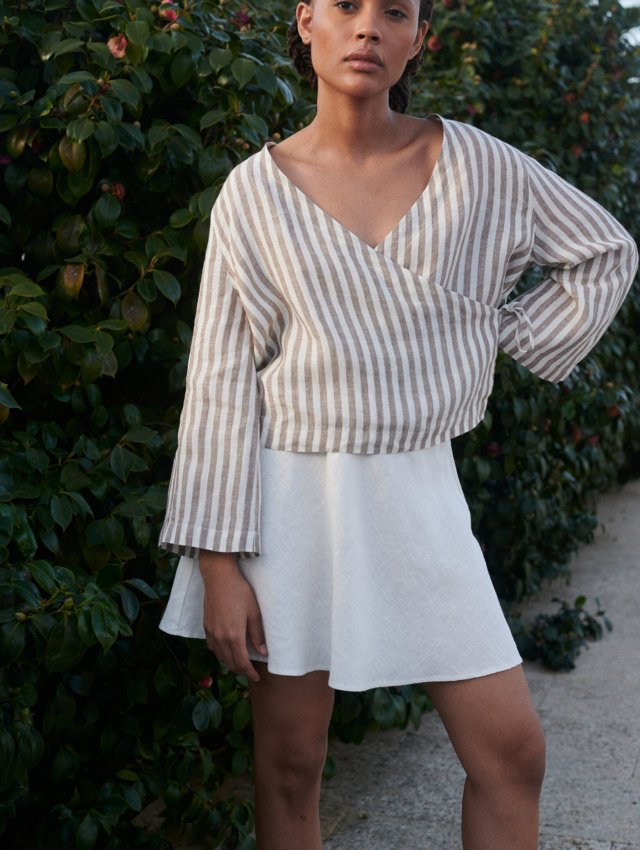 A light linen cacao stripes wrap top paired with a milky white linen short skirt adds a touch of summer style to the woman's look