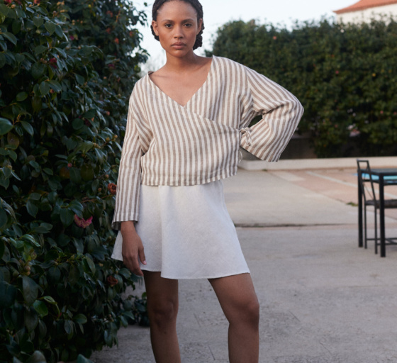 A light linen cacao stripes wrap top paired with a milky white linen short skirt worn by a model