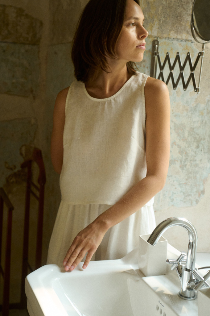Sadie linen top in milky white styled as part of a linen minimalist wardrobe, featuring wide straps and a clean square neckline.”