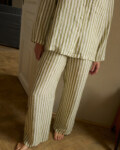 Close up of woman's pajama set of long-sleeved shirt and trousers made from high-quality olive and white stripes linen fabric.