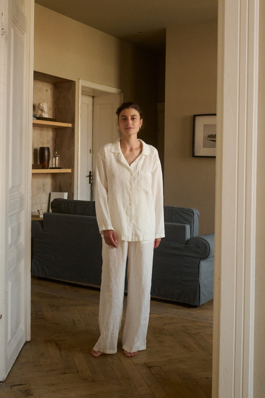 Model wearing a relaxed nightwear set in lightweight milky white linen, featuring a long-sleeve button-up shirt and wide-leg pants