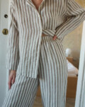 Woman wearing a relaxed cacao stripes lightweight linen set with a long-sleeve button-down shirt and matching wide-leg pants
