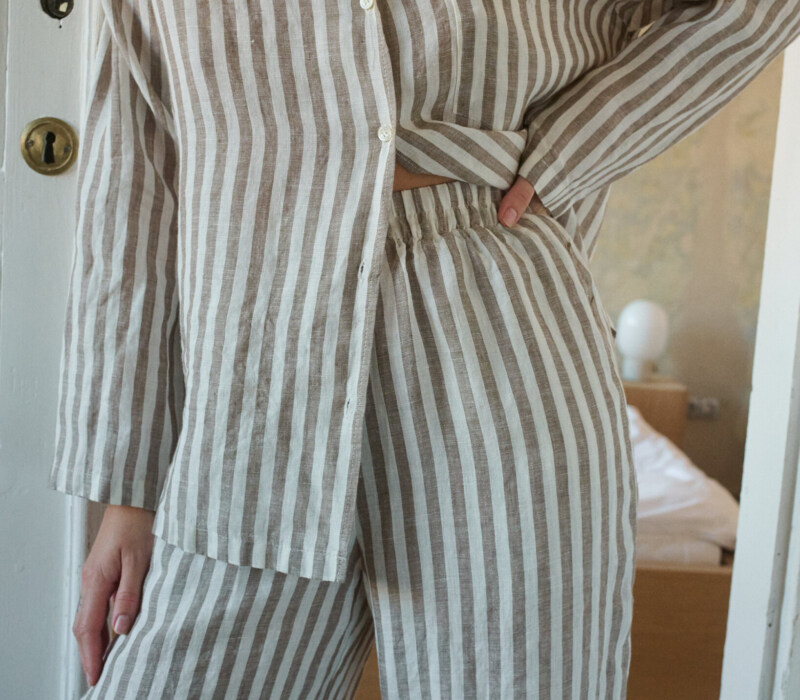Woman wearing a relaxed cacao stripes lightweight linen set with a long-sleeve button-down shirt and matching wide-leg pants