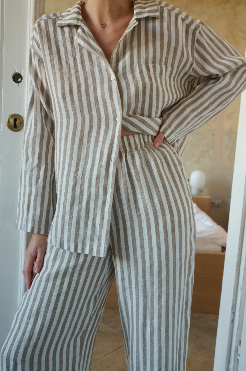 Woman wearing a relaxed cacao stripes lightweight linen set with a long-sleeve button-down shirt and matching wide-leg pants