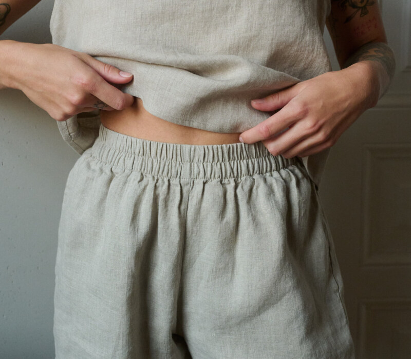 A close up of woman wearing natural grey linen nightwear set. Soft and breathable pajama shorts combined with linen tank top for the most comfort during lounging or sleeping.