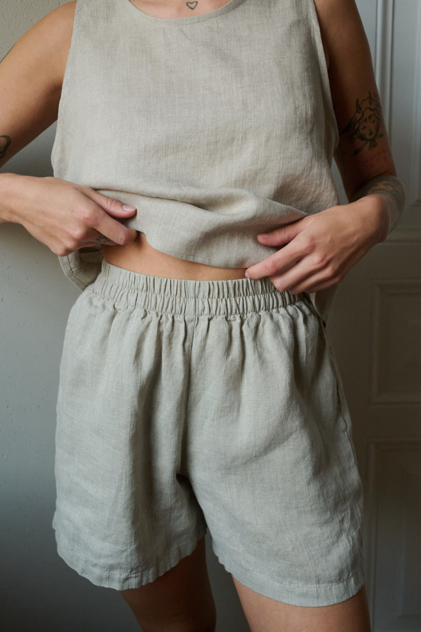 A close up of woman wearing natural grey linen nightwear set. Soft and breathable pajama shorts combined with linen tank top for the most comfort during lounging or sleeping.