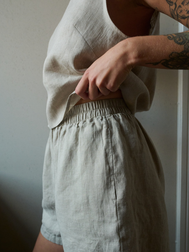 A close up of woman wearing pajama shorts and tank top in natural grey lightweight linen set. Soft and breathable fabric to ensure comfort during sleep and slow living.