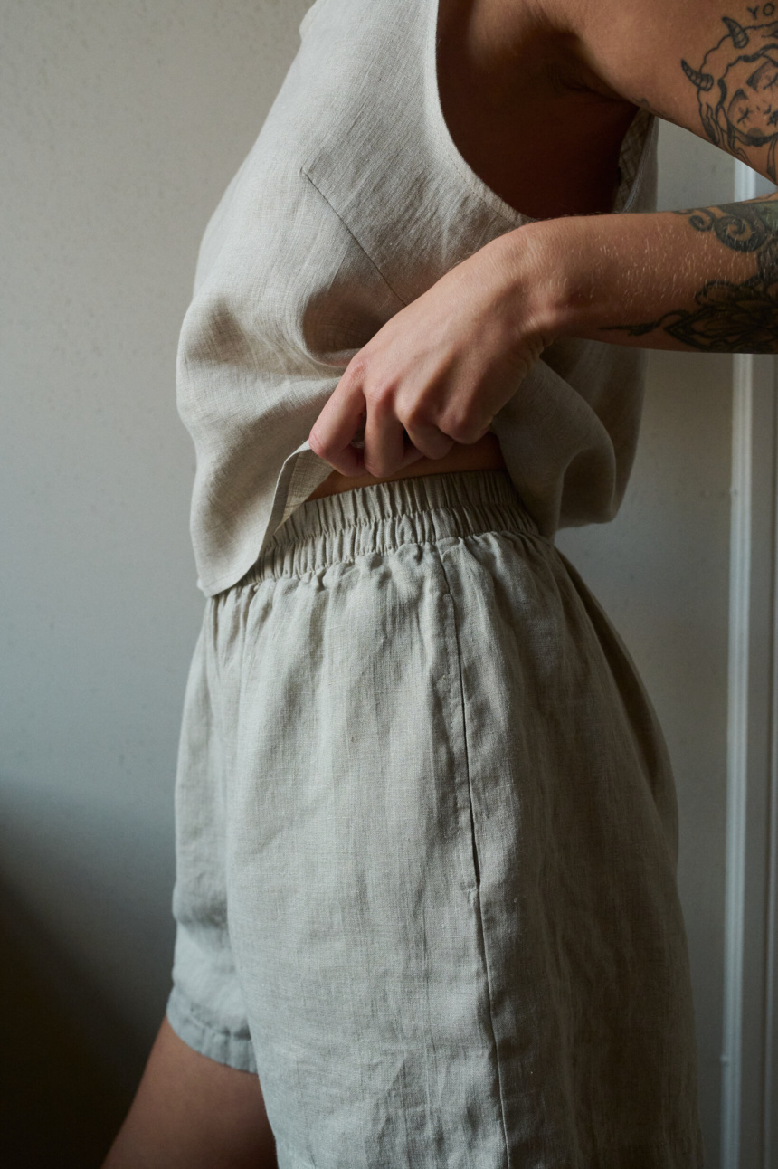 A close up of woman wearing pajama shorts and tank top in natural grey lightweight linen set. Soft and breathable fabric to ensure comfort during sleep and slow living.