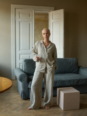 Model wearing high-waisted, wide-leg pants in lightweight natural grey linen and a matching relaxed button-up shirt with shell buttons