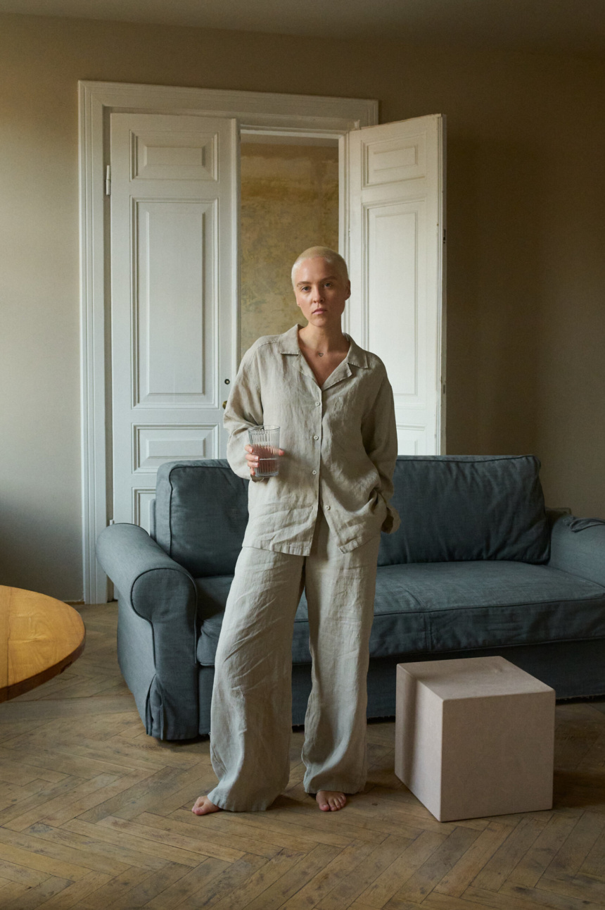 Model wearing high-waisted, wide-leg pants in lightweight natural grey linen and a matching relaxed button-up shirt with shell buttons