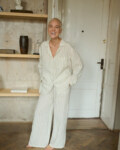 Woman laughing and posing in white and natural grey linen pajama trousers with pockets and long sleeved linen shirt with V-neckline. Breathable and light linen fabric is made for lounging and relaxing at home or beyond.