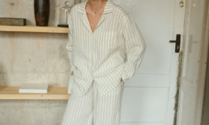 Woman laughing and posing in white and natural grey linen pajama trousers with pockets and long sleeved linen shirt with V-neckline. Breathable and light linen fabric is made for lounging and relaxing at home or beyond.