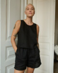 Model wearing a black sleeveless top and matching shorts in lightweight linen, with the shorts featuring pockets