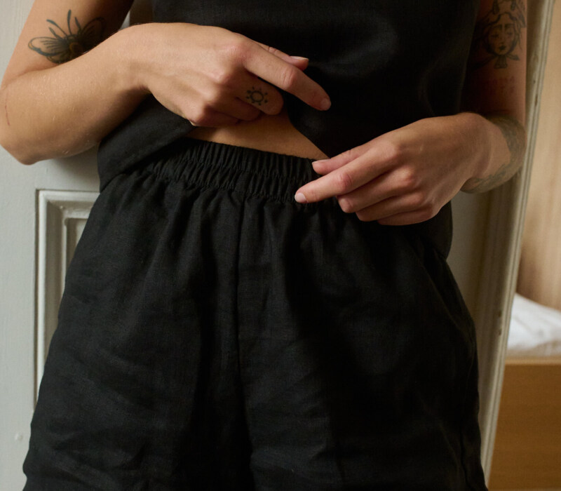 a close up of woman wearing black shorts and top made from lightweight linen fabric. A breathable set of linen nightwear and loungewear for women.