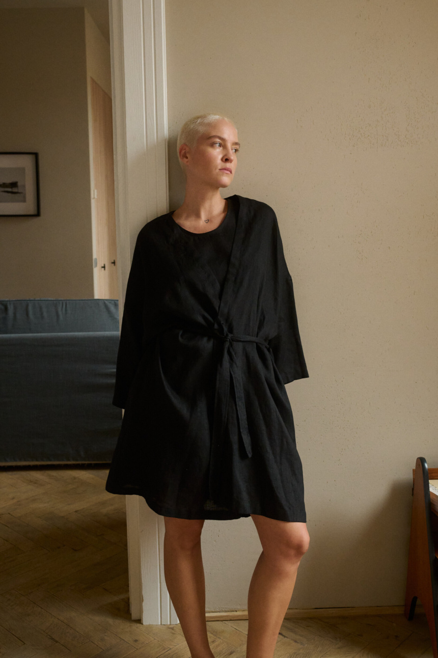 Model wearing a short black lightweight linen robe tied at the waist