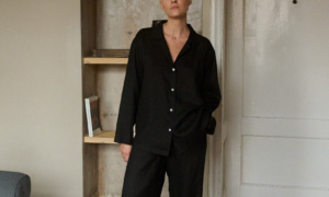 Model wearing a two-piece black lightweight linen set, consisting of a relaxed button-up shirt with a single chest pocket and coordinating wide-leg pants