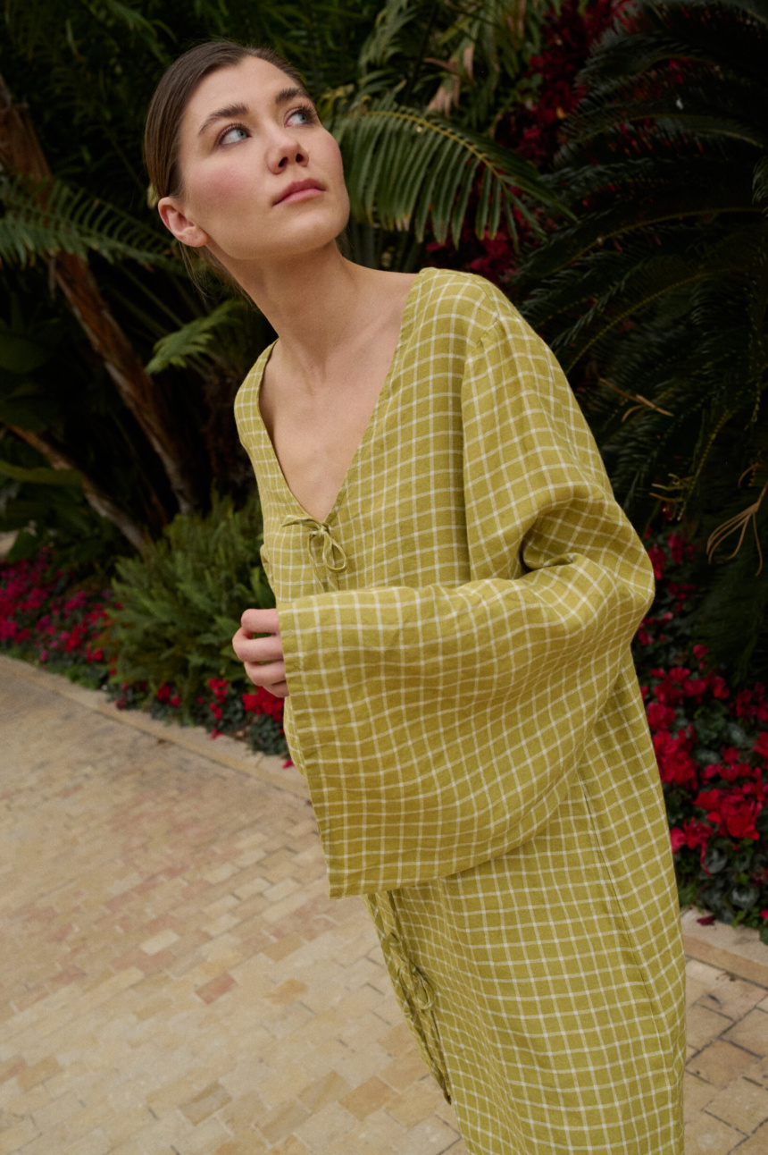 Model wearing a pickle checks linen dress with wide, kimono-style sleeves that flow loosely