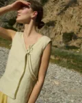 Model wearing a sleeveless V-neck checkered top, designed with a delicate side tie and a relaxed fit that drapes effortlessly