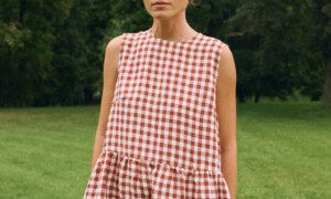 Model in a sleeveless terracotta gingham linen dress with a relaxed drop waist and functional side pockets.