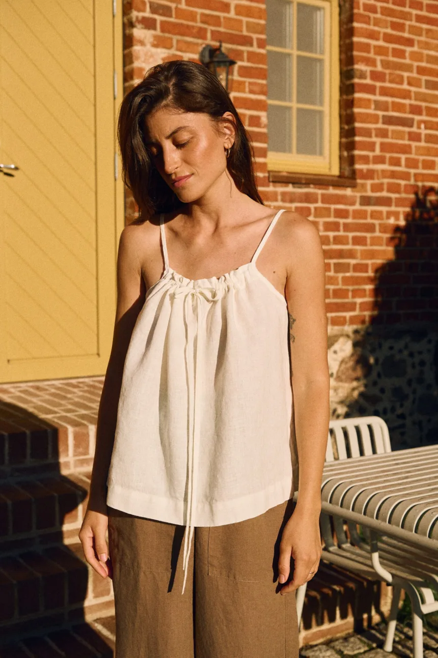 White linen drawstring camisole top paired with wide brown linen trousers