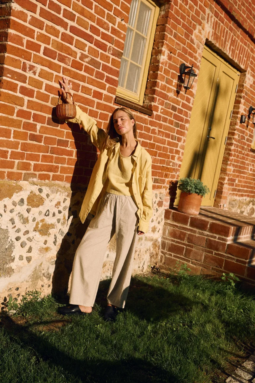 High-waisted natural cotton-linen blend trousers layered with butter yellow linen tank and oversized shirt