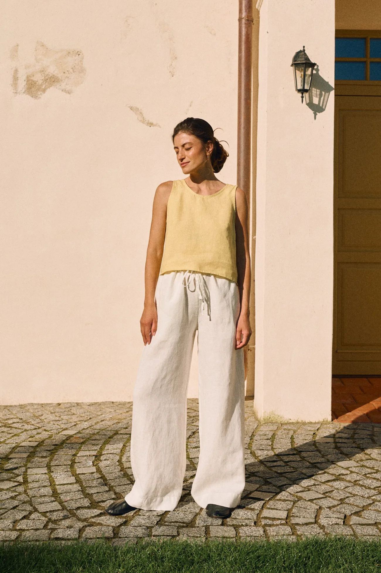 Sleeveless butter yellow linen top paired with white wide-leg linen trousers with a drawstring waist