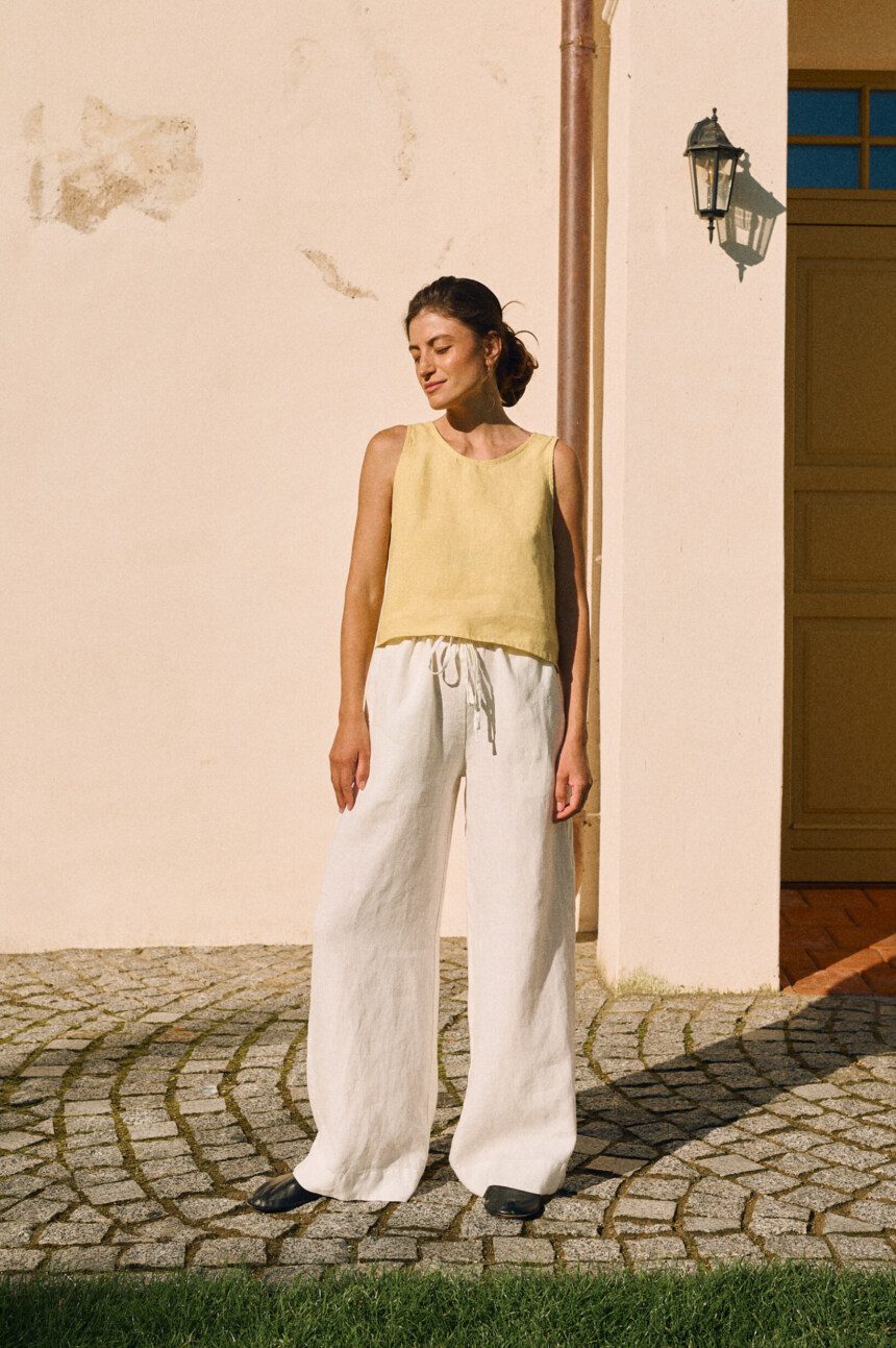 Sleeveless butter yellow linen top paired with white wide-leg linen trousers with a drawstring waist