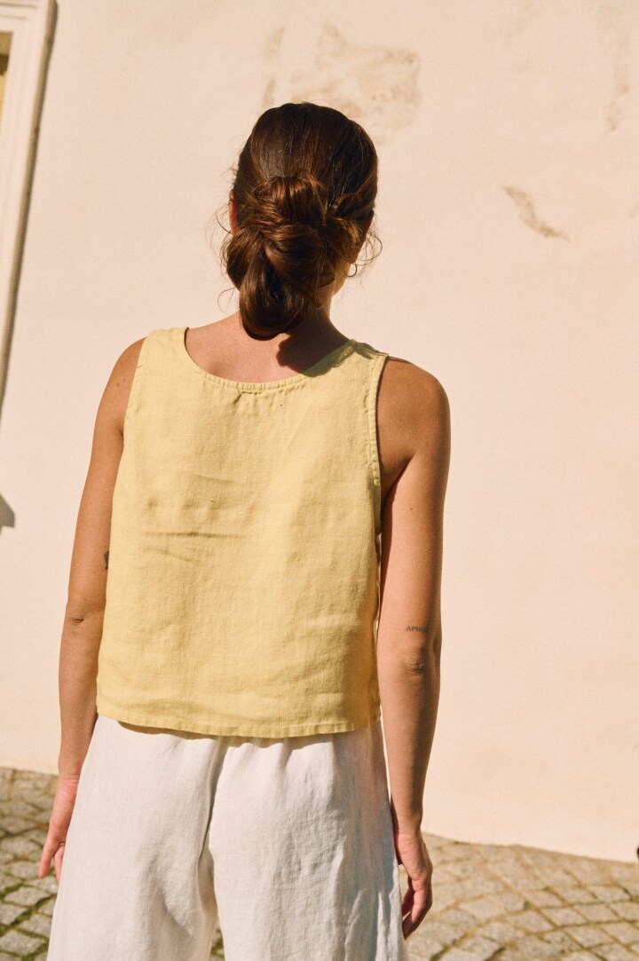 Back view of a sleeveless women’s linen top in butter yellow, featuring a relaxed fit and straight hem