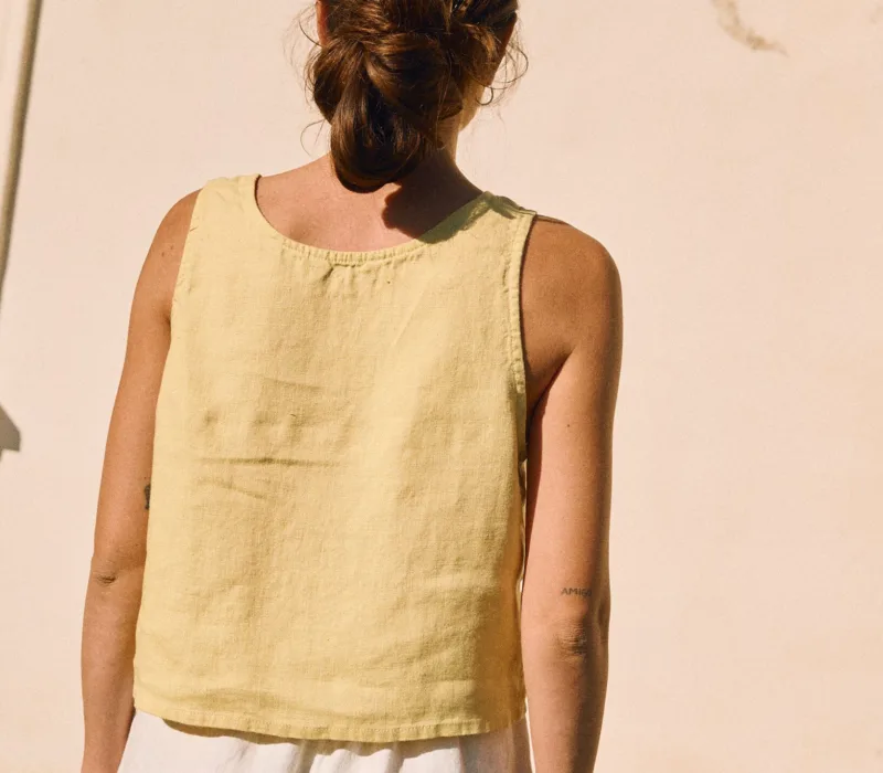 Back view of a sleeveless women’s linen top in butter yellow, featuring a relaxed fit and straight hem