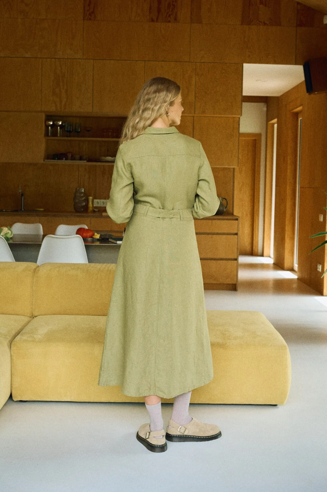 Back view of an olive heavy linen midi shirt dress with a belted waist and long sleeves