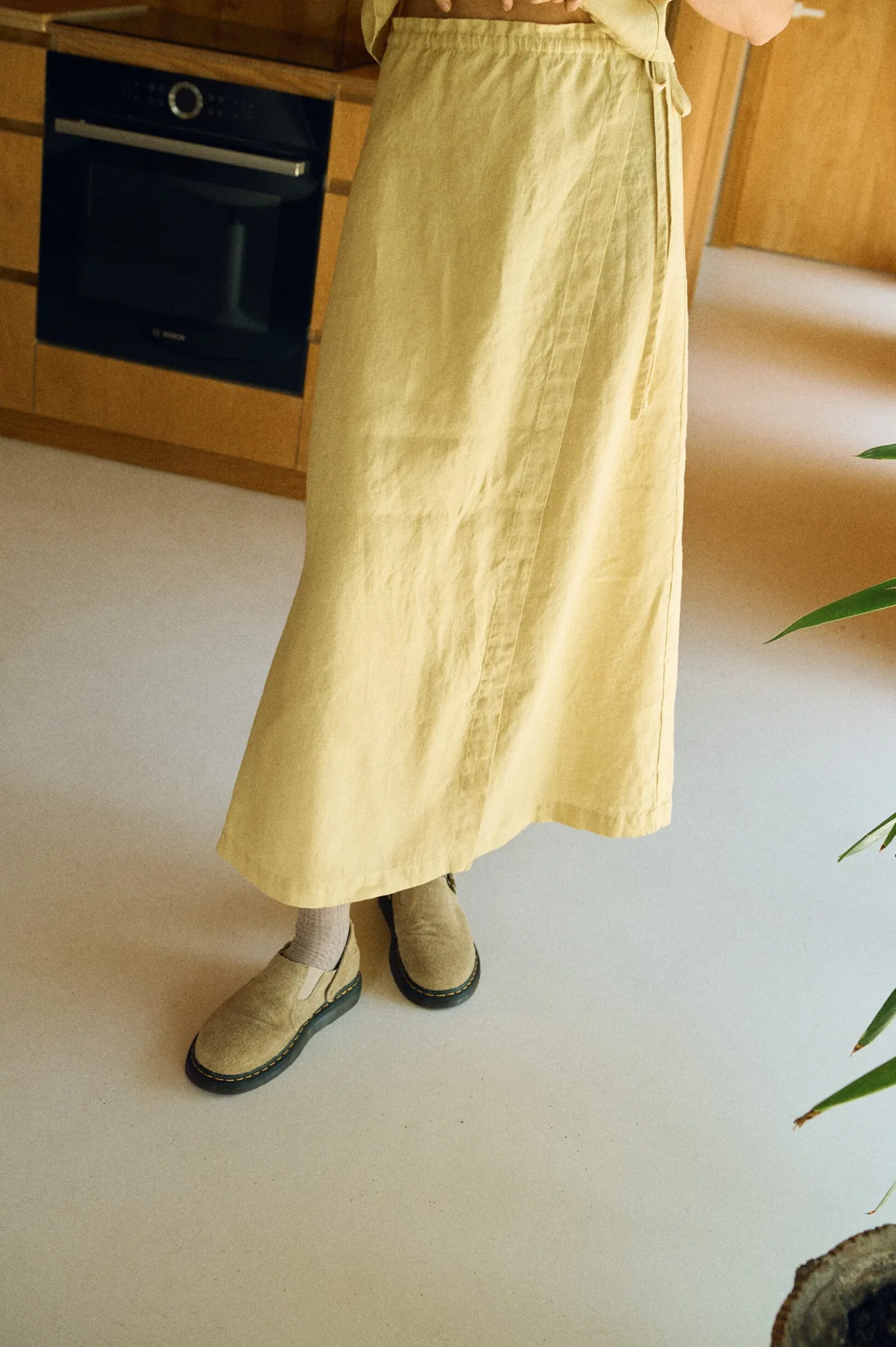 Close-up of a butter-colored linen wrap skirt featuring a flat front and long side ties