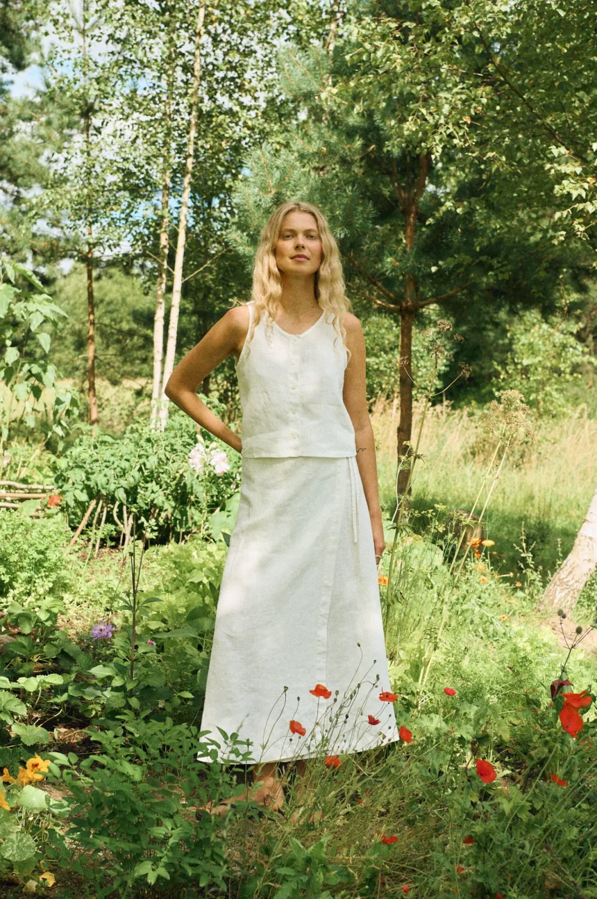 Sleeveless milky white linen set featuring a cropped button-up top paired with a high-waisted A-line wrap skirt