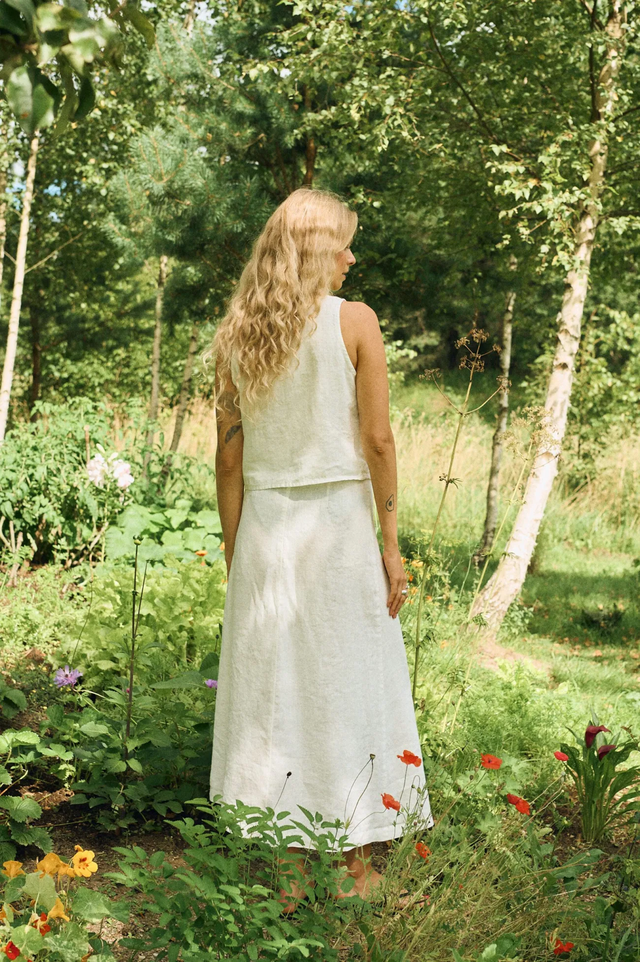 Back view of a white linen sleeveless top paired with a matching white linen wrap skirt