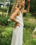 Side view of a woman wearing a white linen sleeveless top paired with a matching white linen wrap skirt