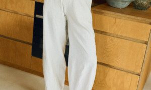 Woman wearing a milky white linen sleeveless button-up top and wide-leg trousers