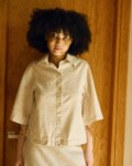 Front view of a natural-toned linen-cotton set featuring a boxy button-up shirt with wide sleeves, paired with a high-waisted midi skirt with a front slit