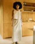 Woman wearing a natural cotton-linen blend ankle-length wrap skirt with a clean A-line silhouette, flat front, and long adjustable ties, paired with a sleeveless button-up top