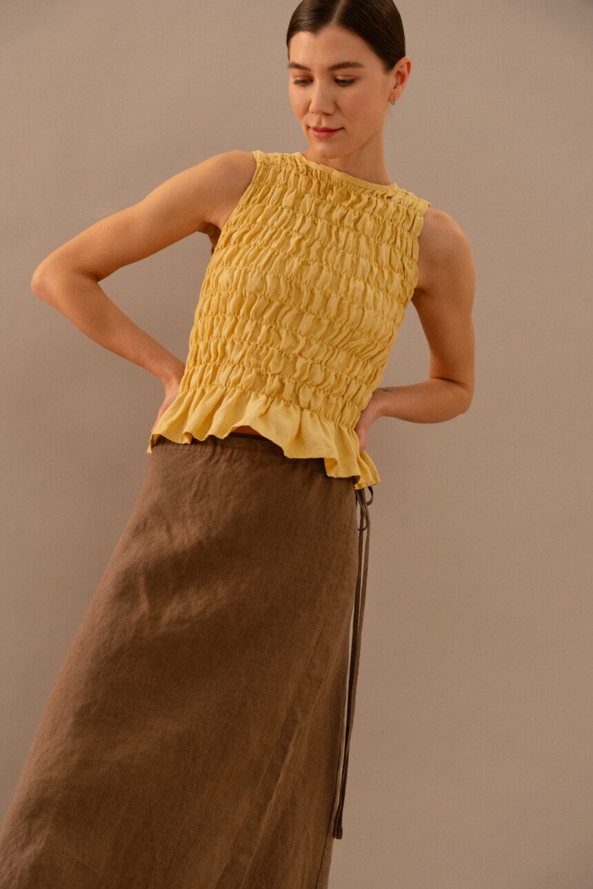 Close-up of yellow linen smocked top showing gathered texture and fitted silhouette