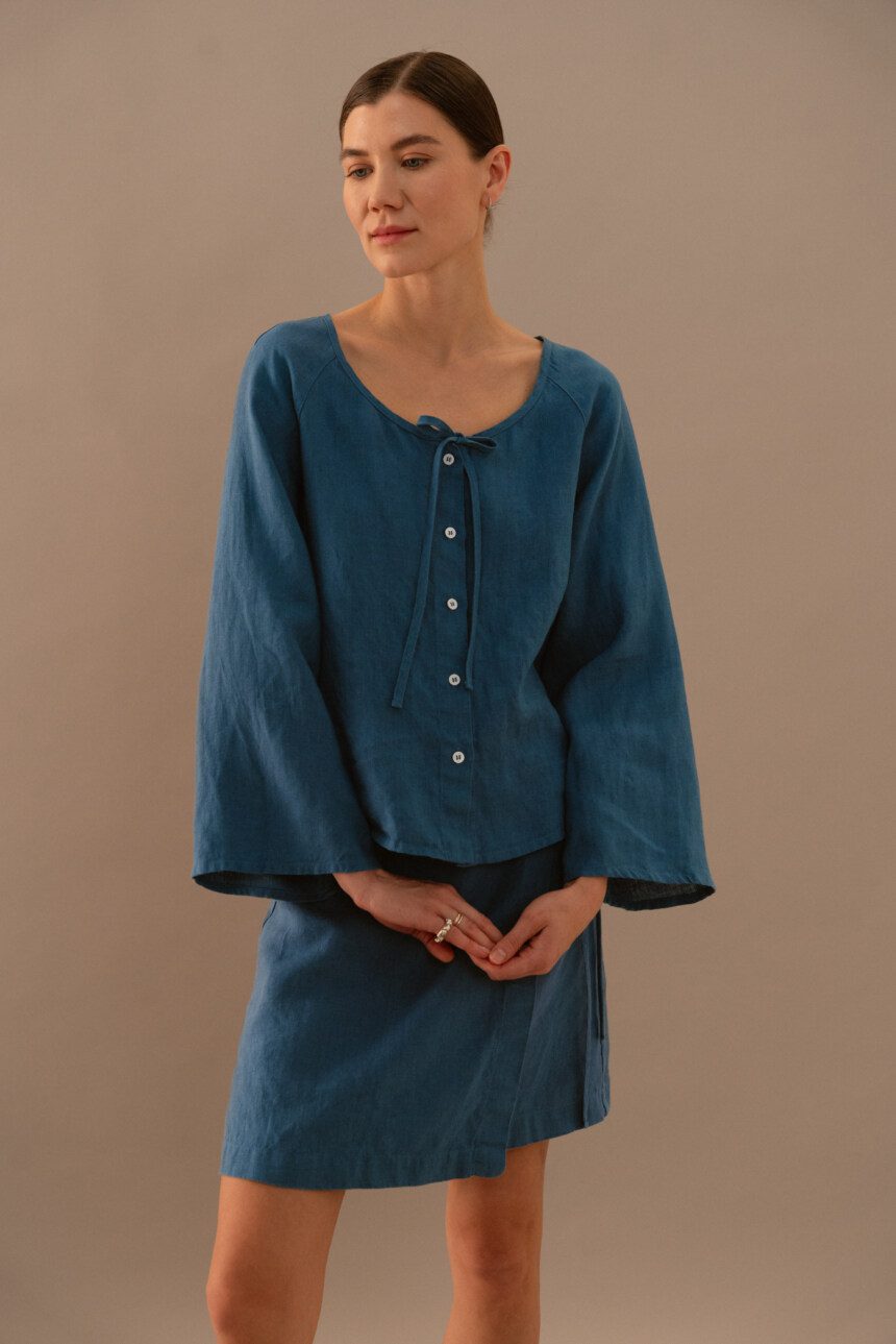 Stellar blue linen blouse with front buttons and tie neckline paired with matching wrap mini skirt